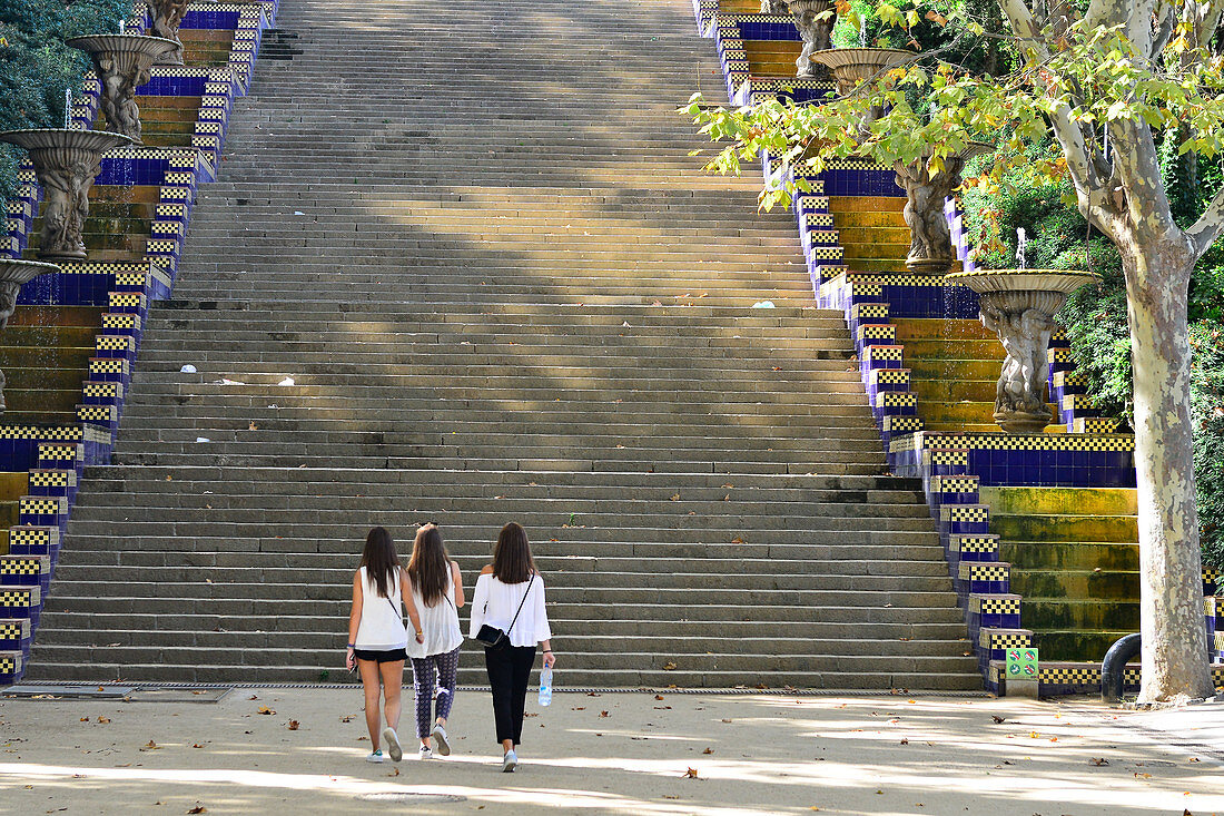 Drei junge Frauen gehen im Park in Richtung einer Treppe, Montjuic, Barcelona, Katalonien, Spanien