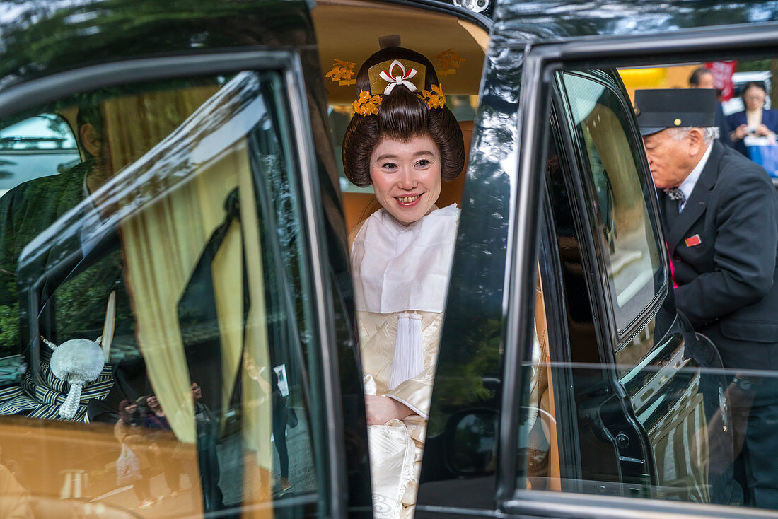 Frau in traditionellem Brautkleid im Auto mit Chauffeur, Tokio, Japan