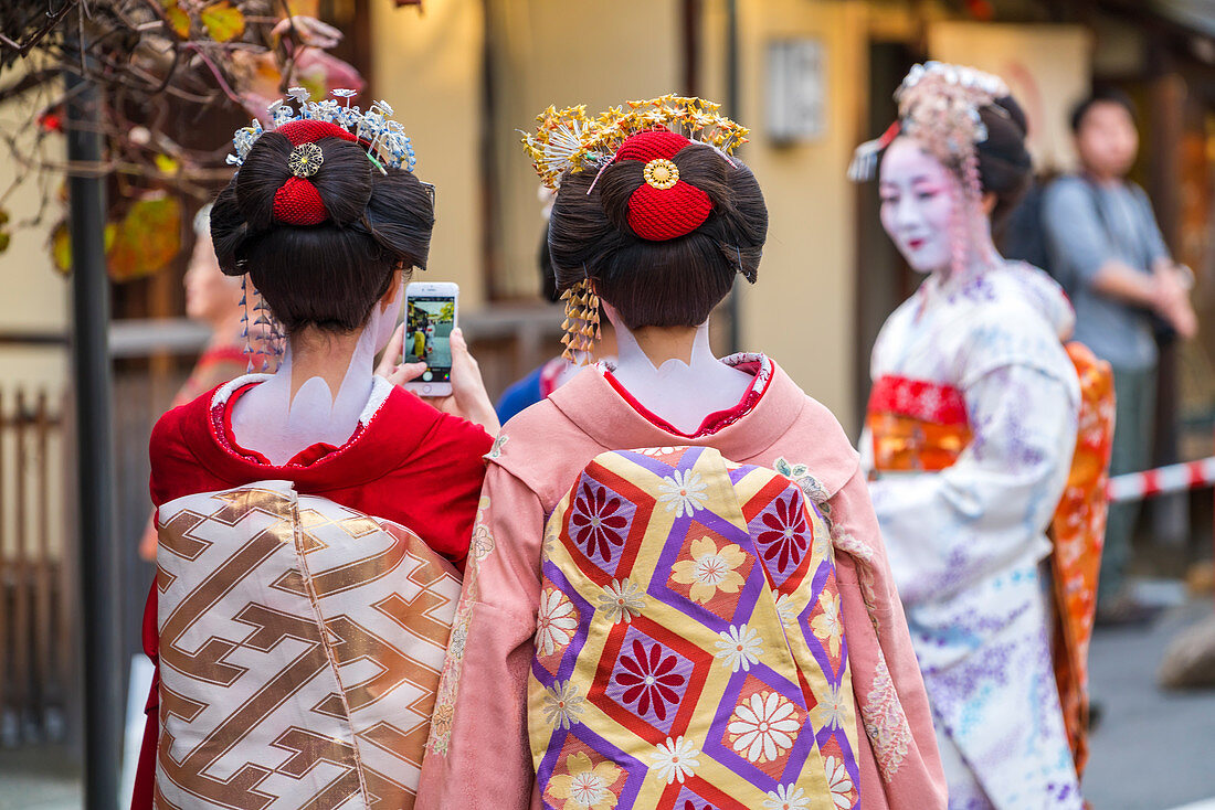 Frauen in traditioneller Geisha-Kleidung beim Fotografieren mit einem Smartphone in Kyoto, Japan