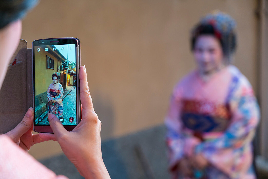 Women dressed in traditional geisha dress being photographed on mobile phone