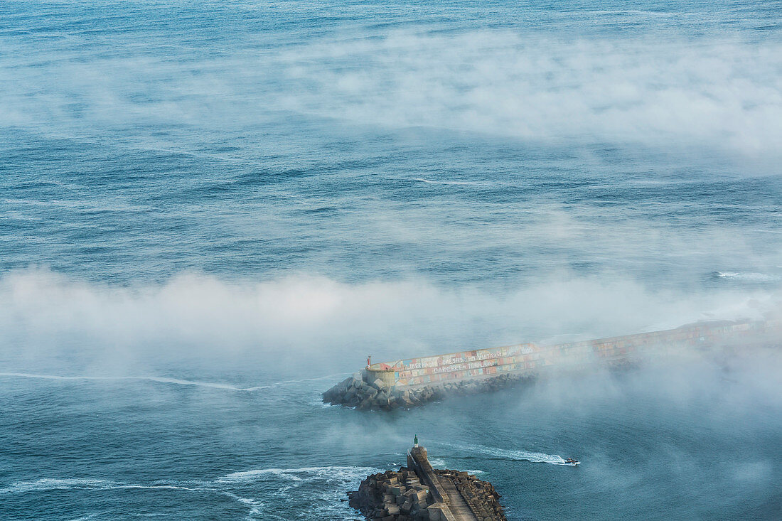 Boat entering harbour in fog, A Guarda, viewed from Santa Tegra Mountain, Galicia, Spain