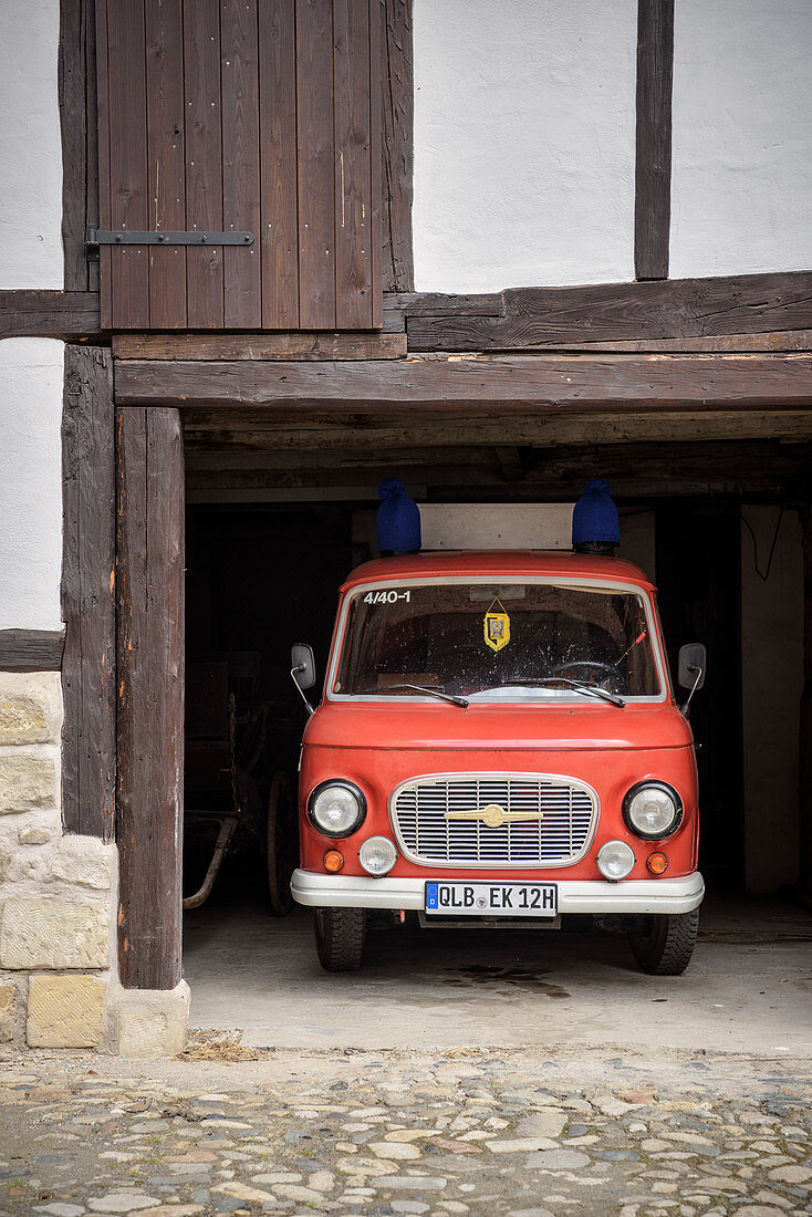 Vintage fire department automobile is parked in garage below a half-timbered house, Quedlinburg, Saxony-Anhalt, Germany, Europe