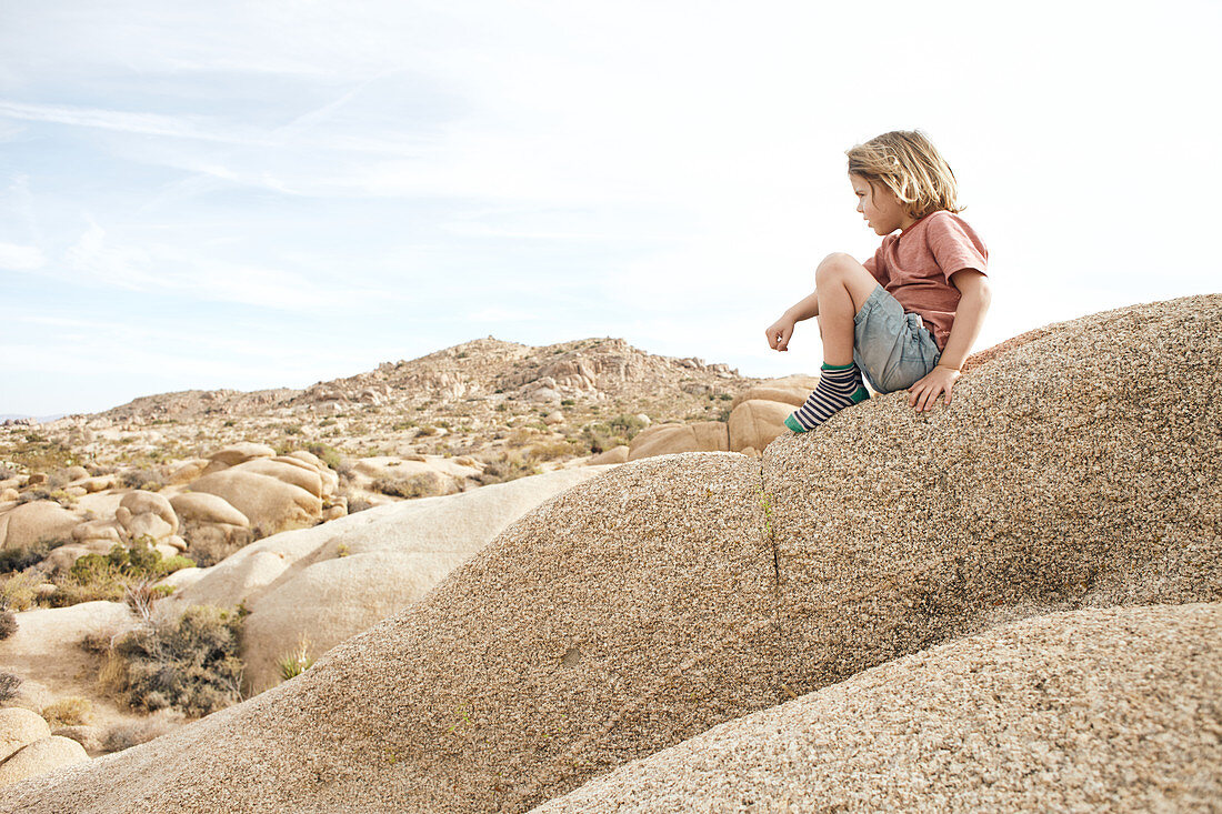 Kleiner Junge sieht sich die Felsenlandschaft der Jumbo Rocks im Joshua Tree Park an, Kalifornien, USA