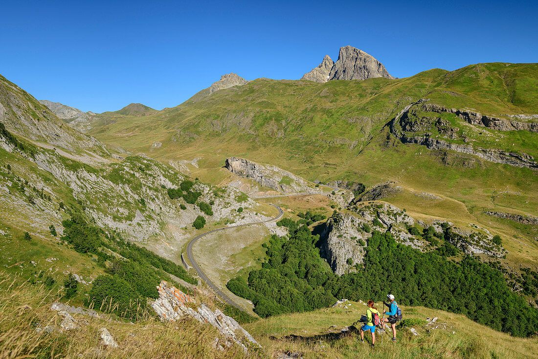 Mann und Frau beim Wandern blicken auf Passstraße Col du Pourtalet, Pic du Midi d´Ossau im Hintergrund, Col du Pourtalet, Nationalpark Pyrenäen, Pyrénées-Atlantiques, Pyrenäen, Frankreich