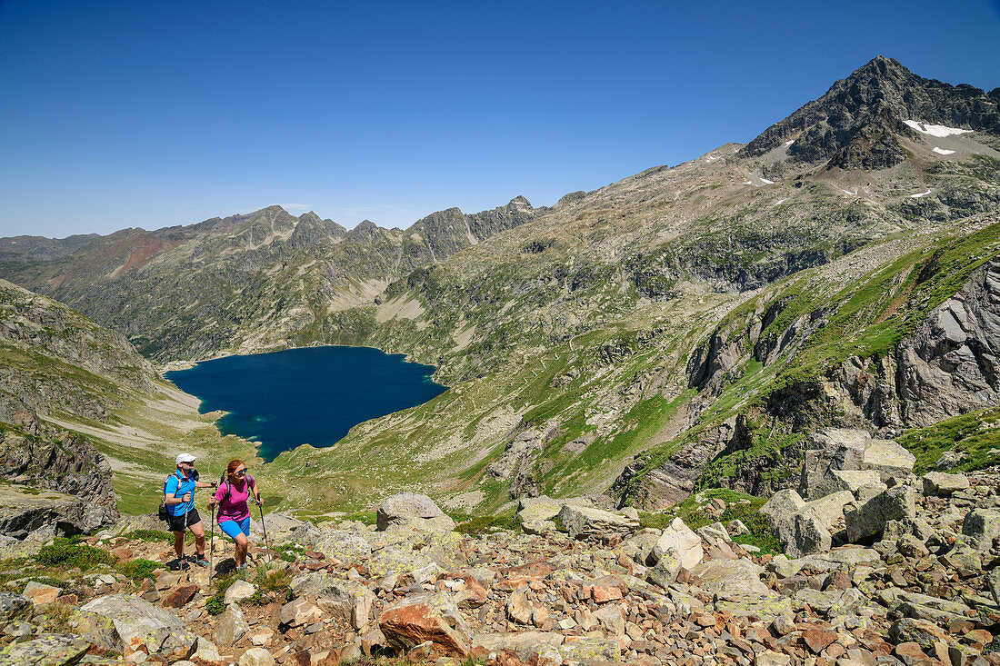 Man and woman hiking up to the Refuge Arremoulit, Lac d´Artouste in the background, Pyrenees National Park, Pyrénées-Atlantiques, Pyrenees, France