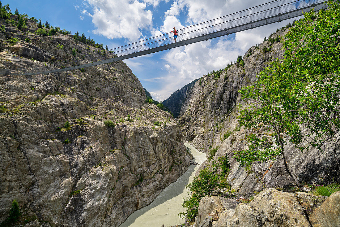 Frau beim Wandern steht auf Aletsch-Hängebrücke, UNESCO Weltnaturerbe Jungfrau-Aletsch, Berner Alpen, Schweiz