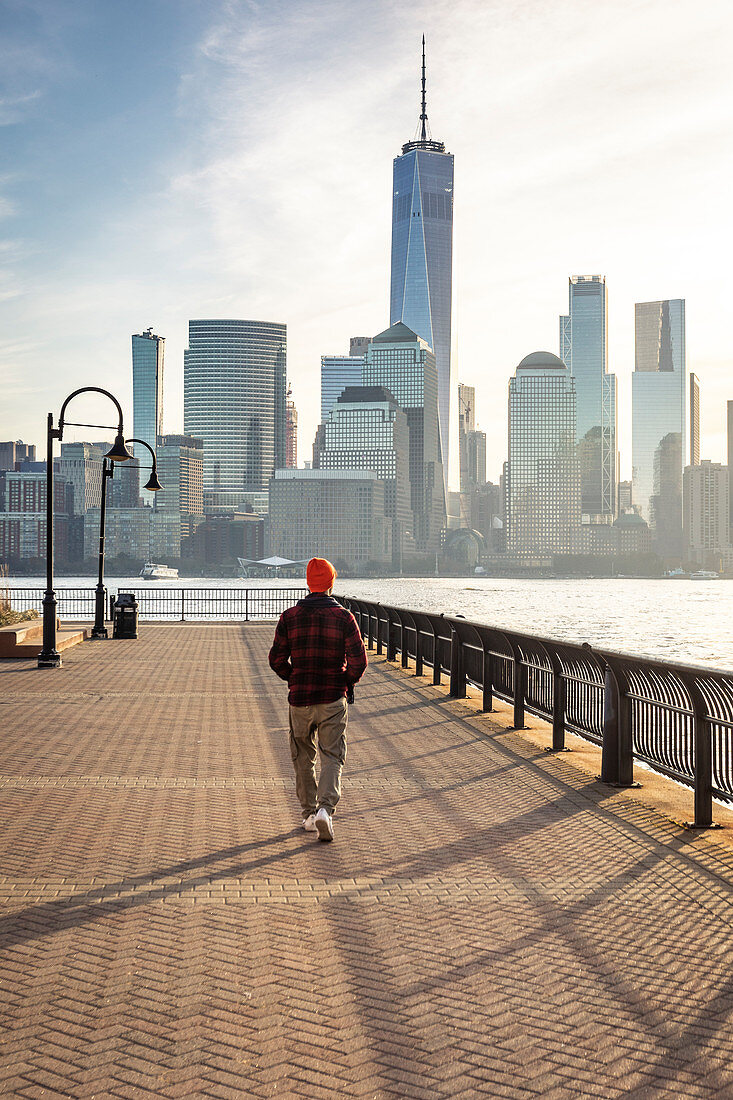 Ein Mann, der die Skyline von Manhattan bei Sonnenaufgang von der Küste von New Jersey bewundert. New York, USA.