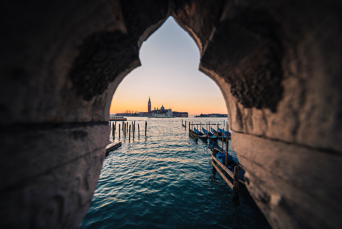 Gondeln nahe Markusplatz mit San Giorgio-Insel auf dem Hintergrund während des Sonnenaufgangs. Venedig, Venetien, Italien.