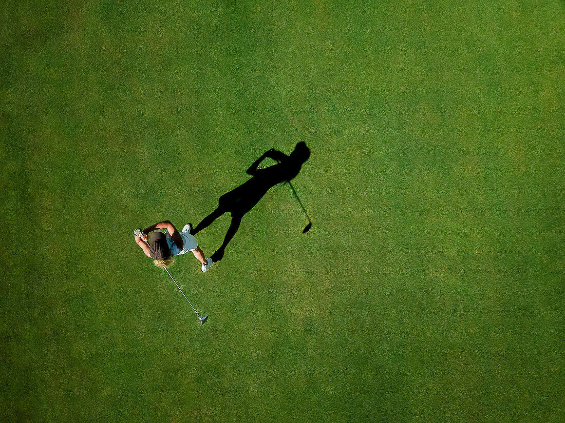 Frau, die Golf auf Golfplatz spielt