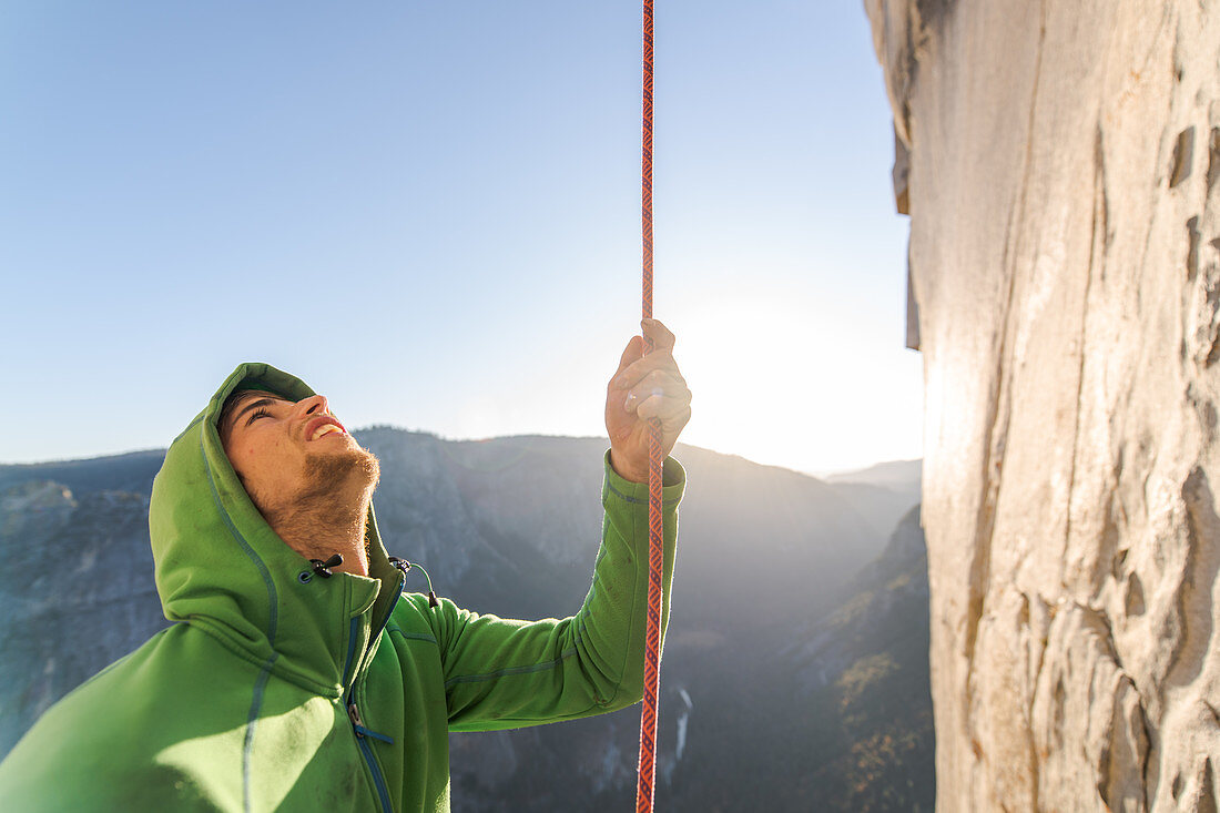 Mountaineer holding onto rope during climb up sheer wall of The Nose, El Capitan, Yosemite National Park.