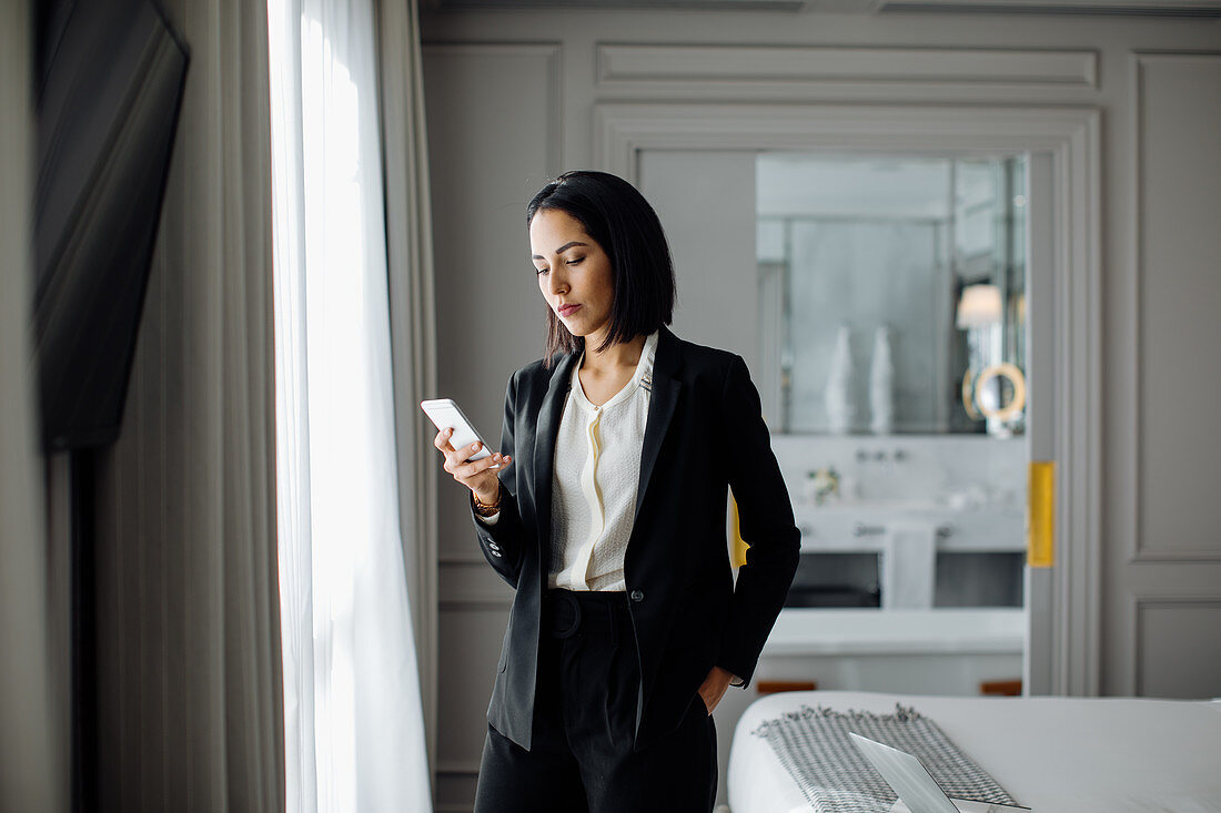 Businesswoman using smartphone in suite