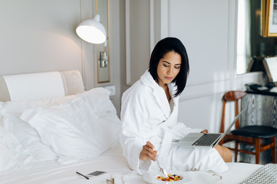 Frau mit Laptop und Frühstück in einer Suite