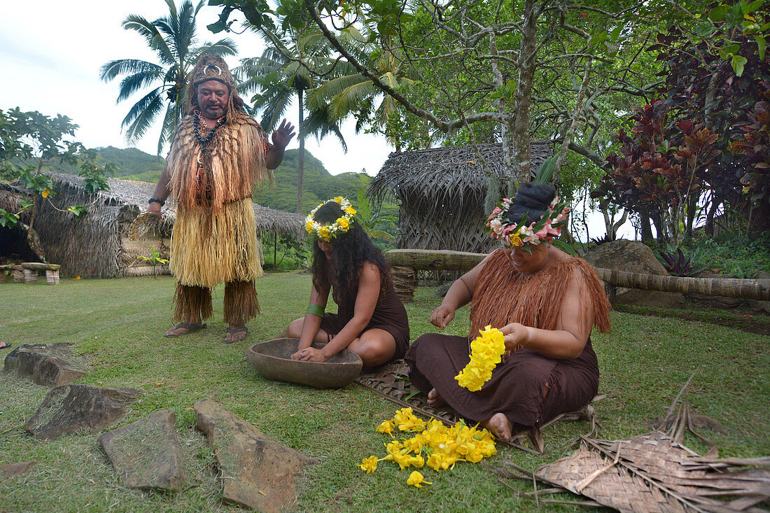 RAROTONGA - 16. JANUAR 2018: Der Stammeshäuptling der Cook-Insulaner steht neben zwei Cook-Insulanerinnen, die im Freien in einem Maori-Dorf im Hochland von Rarotonga, Cookinseln, arbeiten