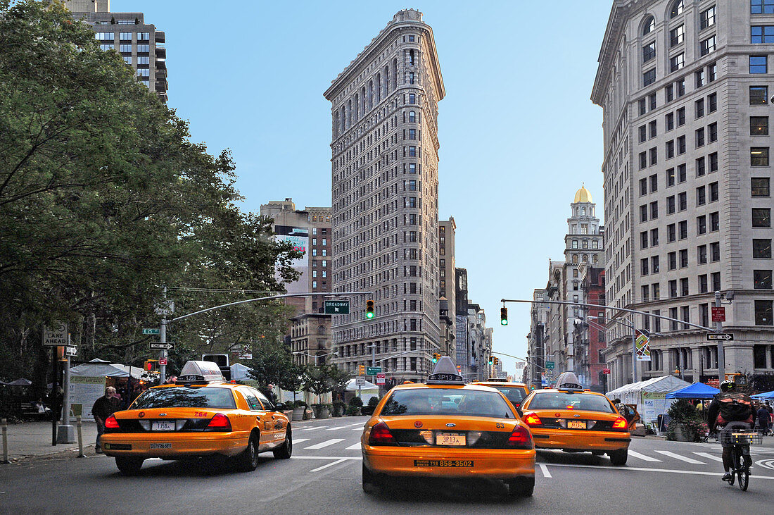 NEW YORK CITY - OCT 10 2009: New York yellow taxi cabs rush through Fifth Avenue under the Flatiron Building in the Midtown Manhattan of New York City.