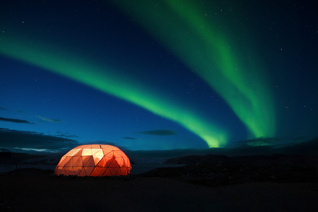 Illuminated tent with northern Lights,Qaleraliq Glacier Camp, Greenland