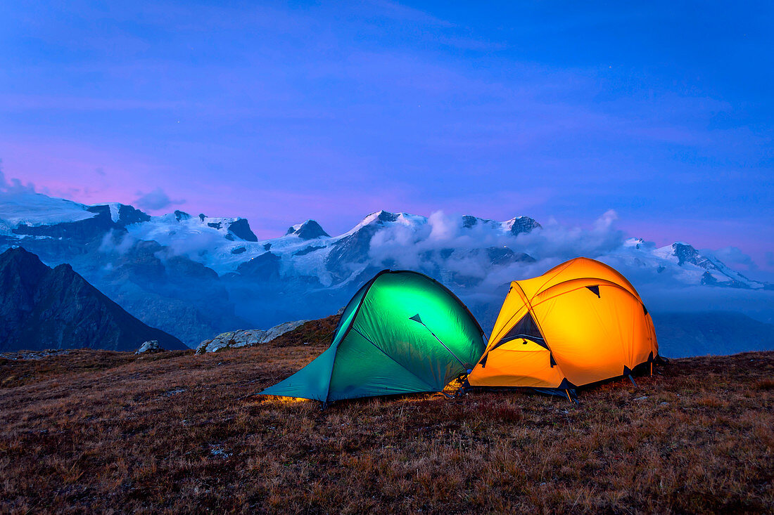 Sonnenuntergang mit beleuchteten Zelten oben auf Facciabella, Monte Rosa auf Hintergrund, Val d'Ayas, Aostatal, Italien, Europa
