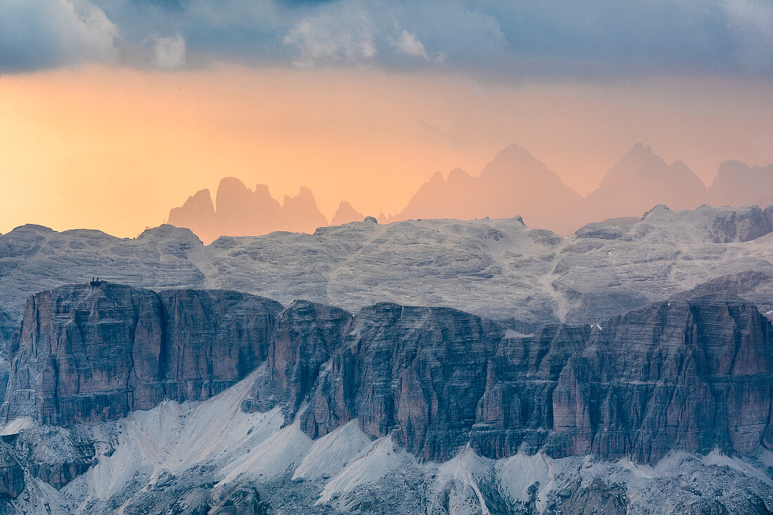 Die Sella-Gruppe von Marmolada bei Sonnenuntergang gesehen, auf dem Hintergrund in der Silhouette von links die Gran Fermeda, Sass Rigais und Furchetta in der Geislergruppe, Dolomiten, Südtirol, Italien