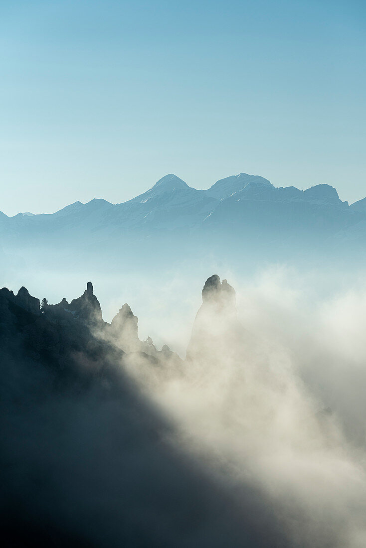 Gardena Pass, Dolomiten, Bezirk Bozen, Südtirol, Italien, Europa. Nebel treibt um einige Felsen, im Hintergrund die Berge von Tofana di Mezzo und Tofana di Dentro