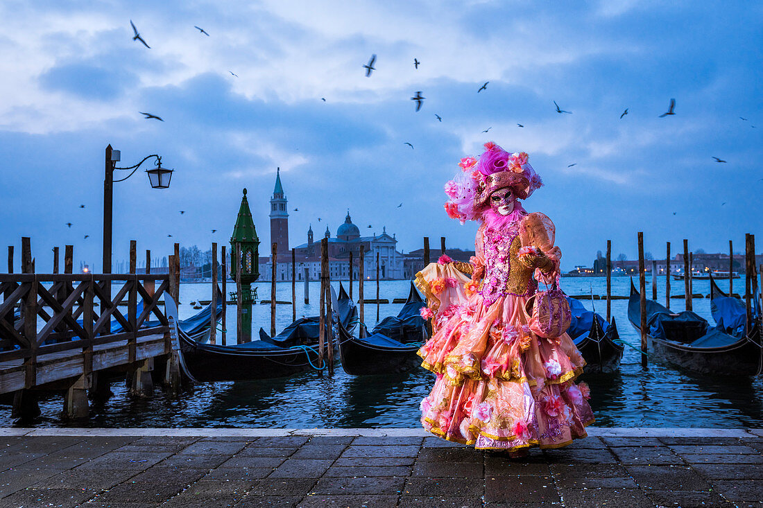 Typical mask of Carnival of Venice in Riva degli Schiavoni with St. George's island in the background, Venice, Veneto, Italy