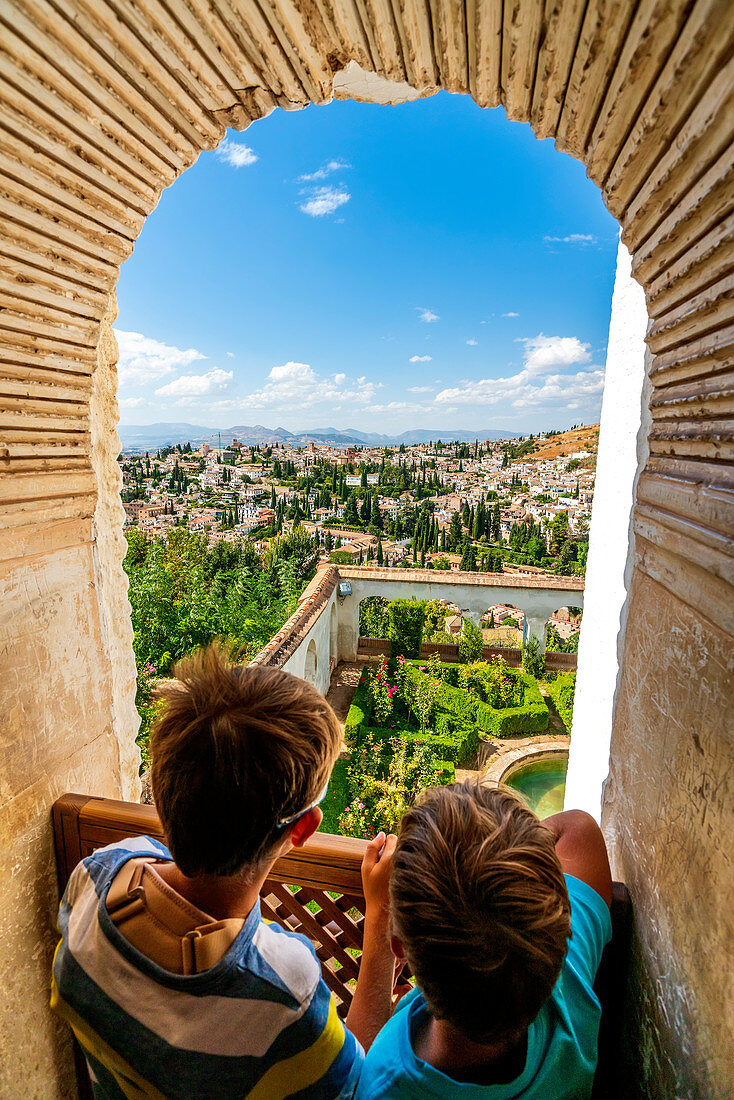 Two children look at Patio de la Sultana (Court of the Sultana’s Cypress Tree) from mirador on top of Generalife Palace, Granada, Andalusia, Spain