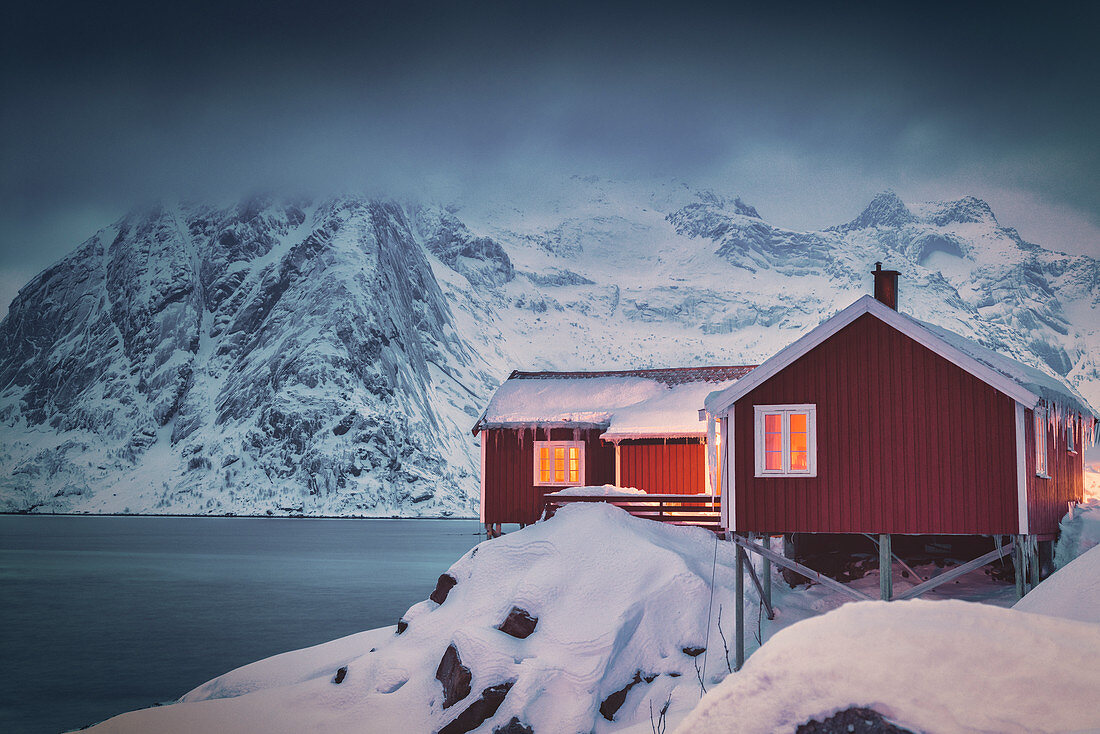 Rote Fischerhütten bedeckt mit Schnee, Hamnoy, Nordland, Lofoten Inseln, Norwegen