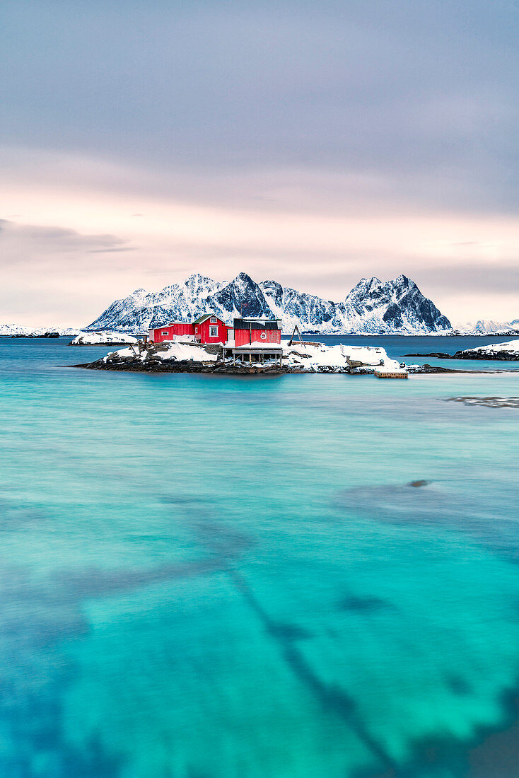 Rorbu auf schneebedeckter Insel im türkisfarbenen Meer, Svolvaer, Lofoten-Inseln, Norwegen