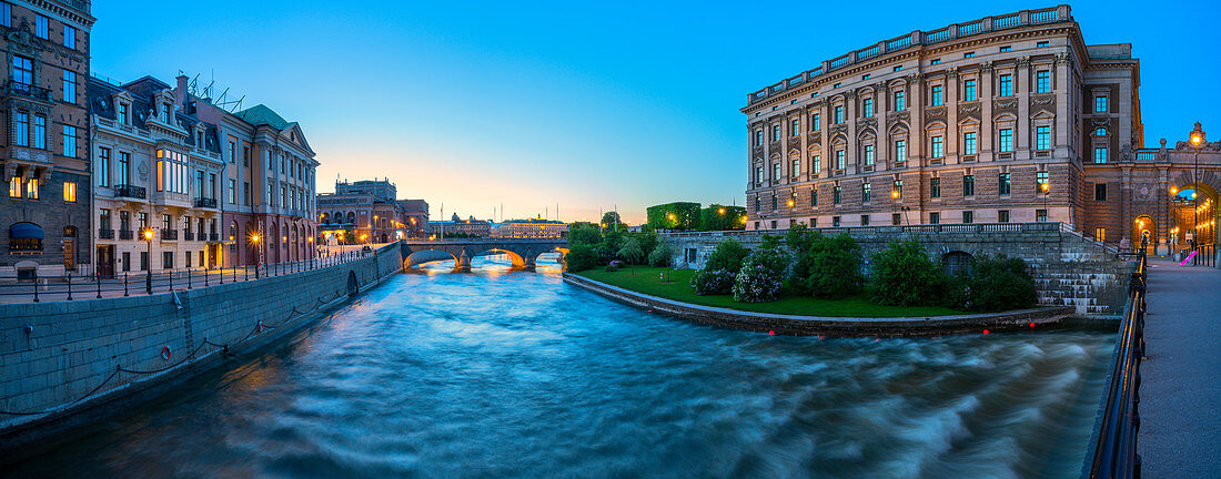 Panorama des Parlamentshauses (Riksdagshuset) und des Opernhauses in der Abenddämmerung von der Riksbron-Brücke entlang des Norrstrom-Flusses, Stockholm, Schweden