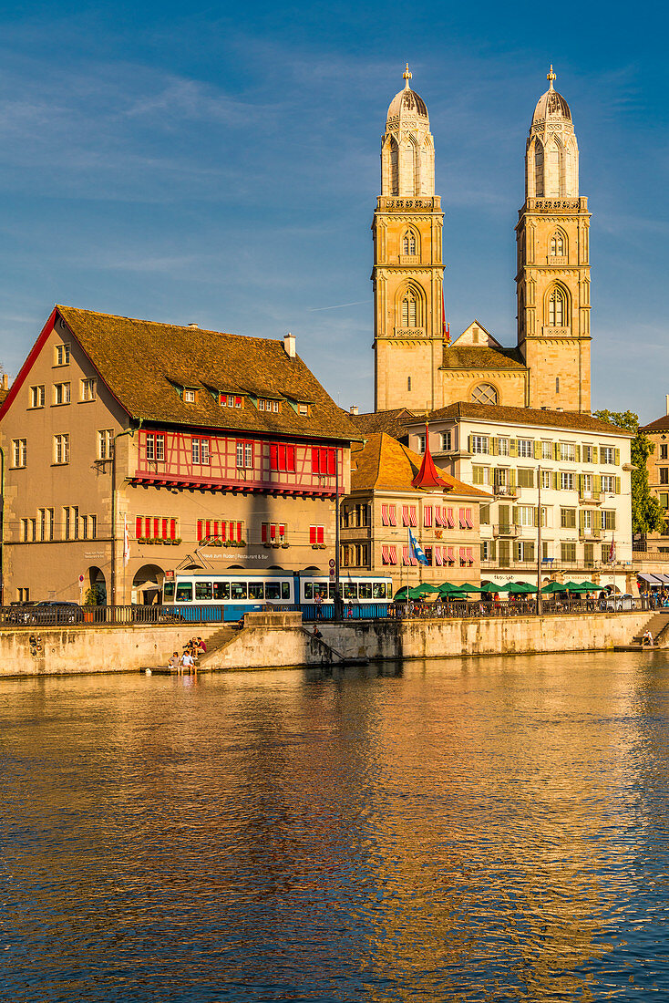 Tram at Limmatquai on banks of Limmat River with Grossmunster church in background, Zurich, Switzerland