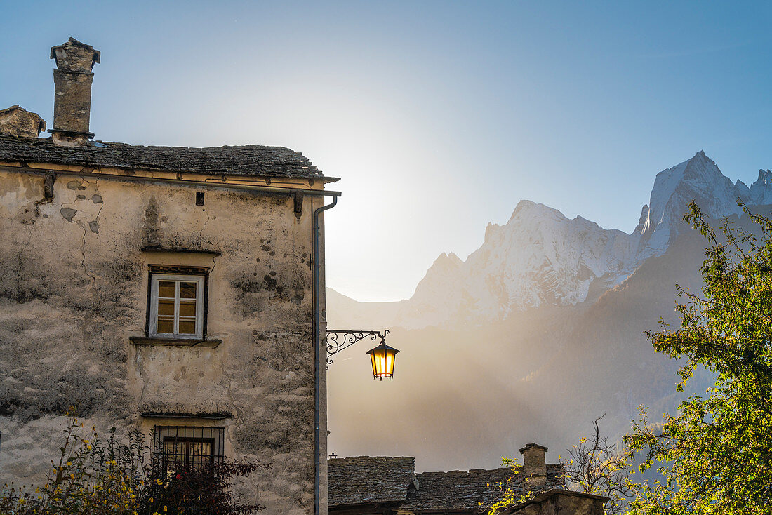 Nebliger Sonnenaufgang über dem traditionellen Steinhaus im alten Dorf Soglio, Kanton Graubunden, Schweiz