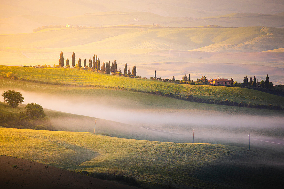 A farmhouse in the  morning between Val d'Orcia Hills. San Quirico d'Orcia, Val d'Orcia, Siena Province, Tuscany, Italy.
