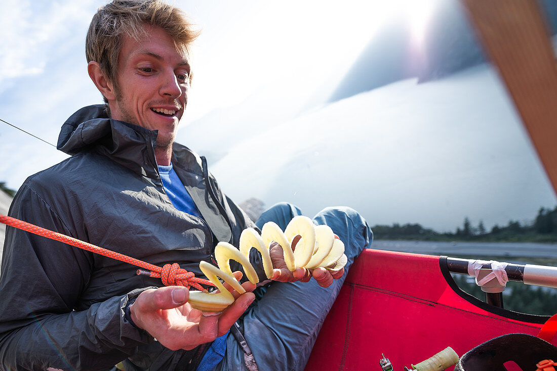 Climber playing with potato twister on portaledge against flaring sun,Squamish,British Columbia,Canada