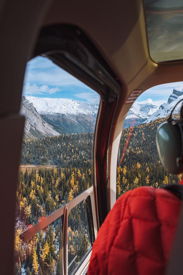 Hubschrauber über den kanadischen Rocky Mountains mit Lärchen, die im Herbst gelb werden, Alberta, Kanada