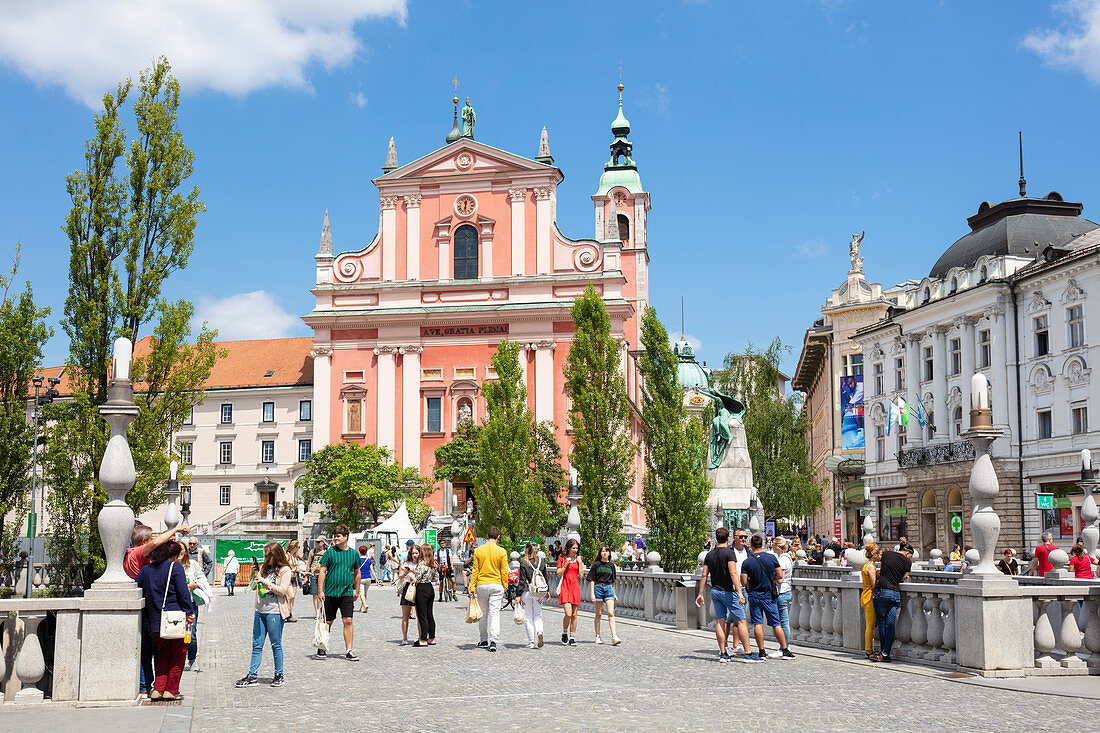Die rosa Franziskanerkirche in Preseren Square und Touristen, die über die Dreifachbrücke, Zentral-Ljubljana, Slowenien, Europa gehen