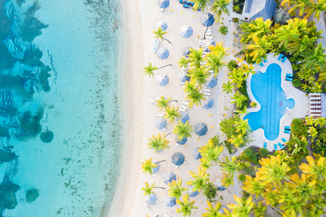Schwimmbad und Sonnenschirme auf weißem Sandstrand von oben durch Drohne, Morris Bay, alte Straße, Antigua, Inseln über dem Winde, Westindische Inseln, Karibik, Mittelamerika