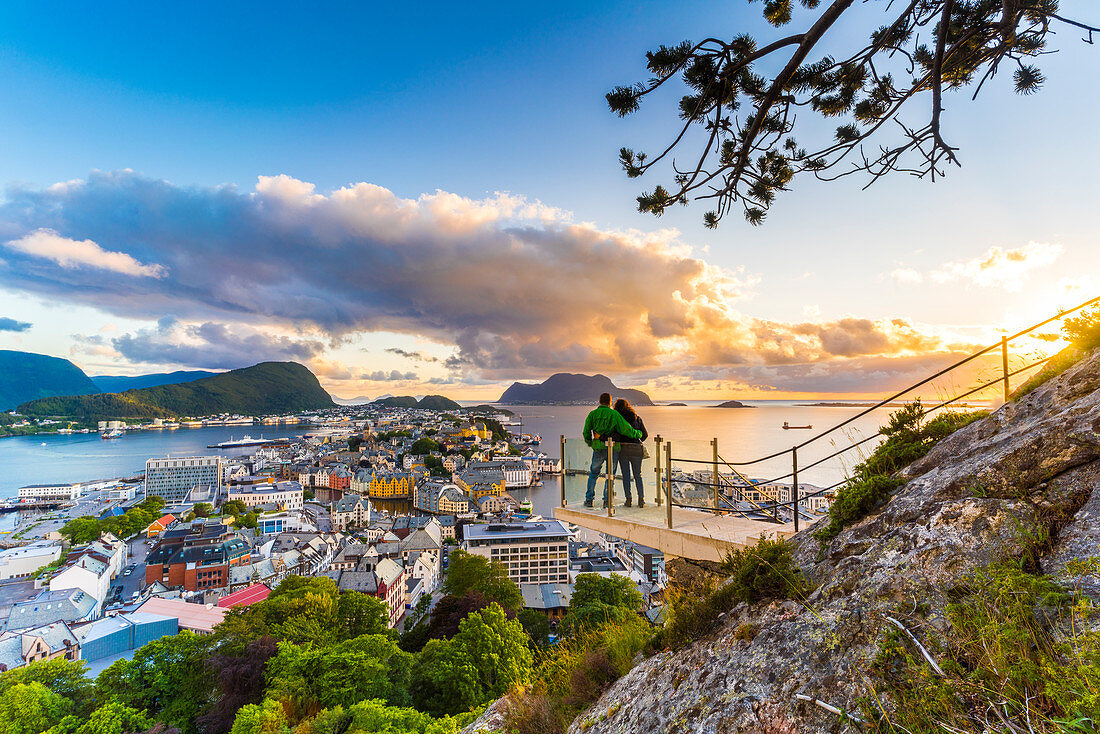 Couple embracing and enjoying the view of Alesund at sunset from Byrampen viewpoint, More og Romsdal county, Norway, Scandinavia, Europe