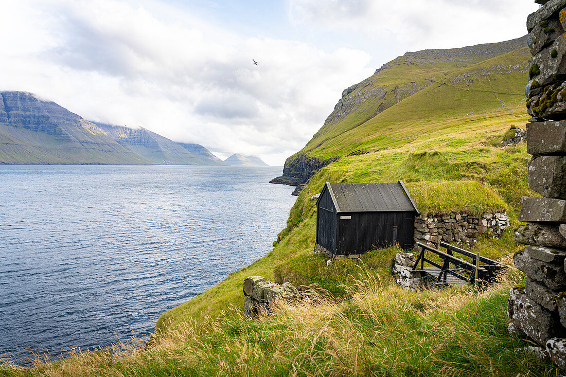 View of a boathouse from Mikladalur to the south to the islands of Kunoy and Bordoy, Mikladalur, Kalsoy, Faroe Islands, Denmark.