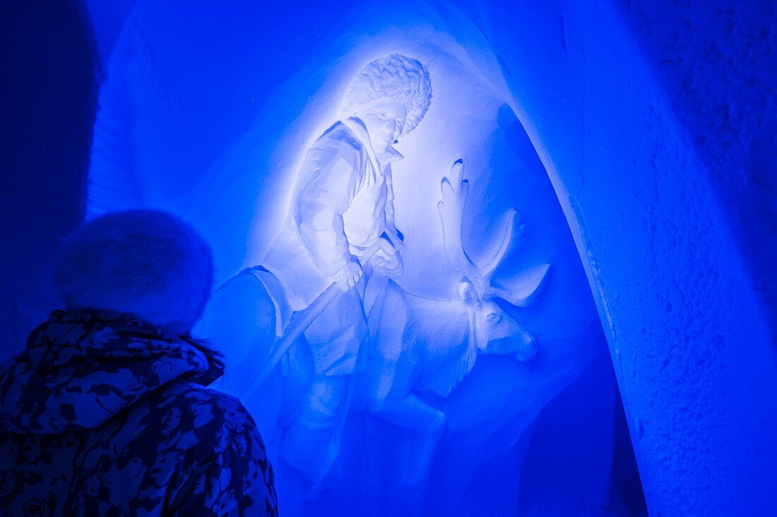 Frankreich, Savoie, Tarentaise-Tal, Vanoise-Massiv, Skigebiet Arcs 2000, Frau, die das Basrelief eines mongolischen Rentierzüchters im Schnee der Wand der Galerie mit Skulpturen des Iglu-Dorfes während der Wintersaison 2017-2018 beobachtet