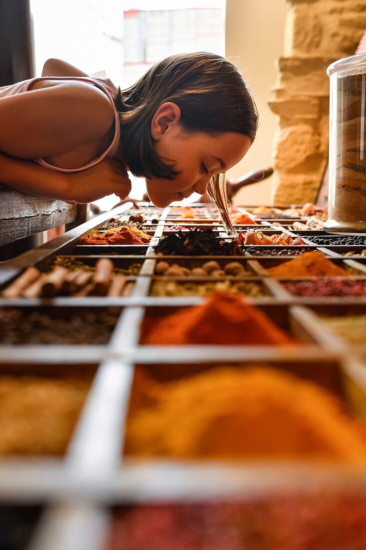France, Ille et Vilaine, Cancale, little girl smelling spices in the famous Roellinger delicatessen spice store