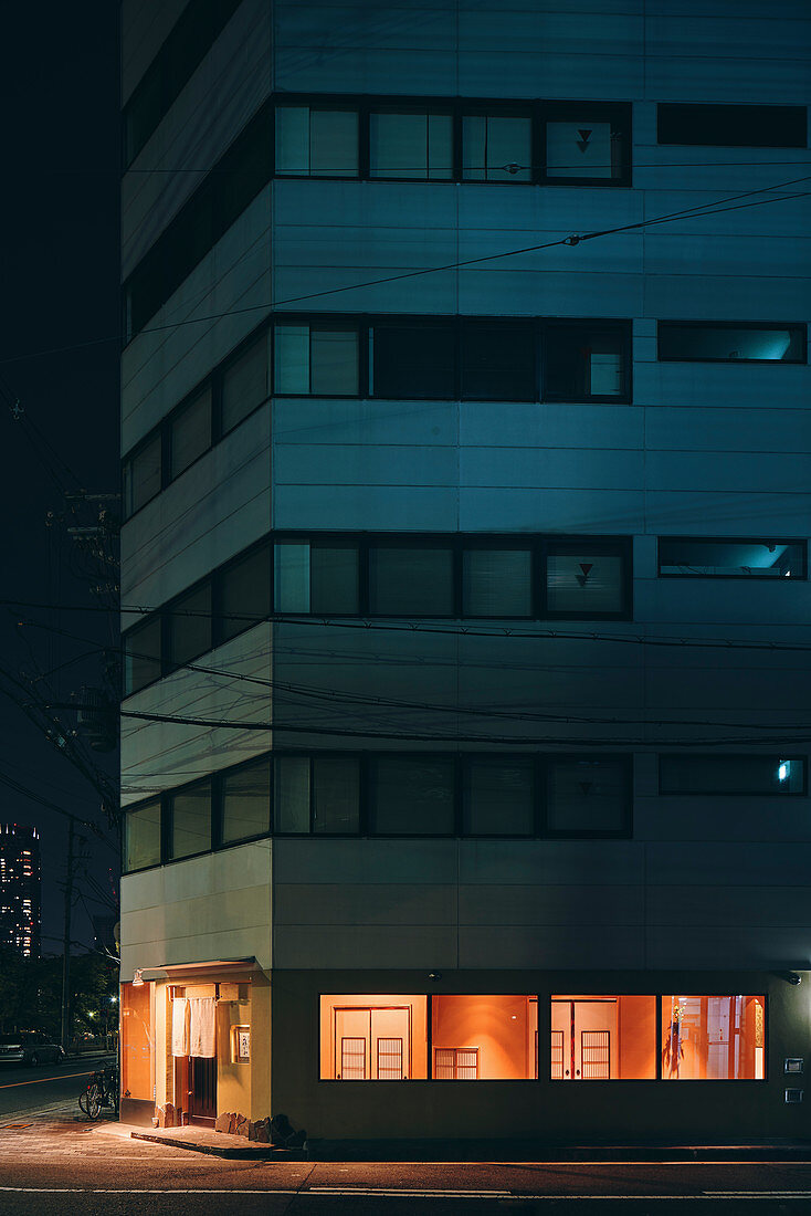 Nachtszene eines Wohnhauses mit beleuchtetem Erdgeschoss, Osaka, Japan
