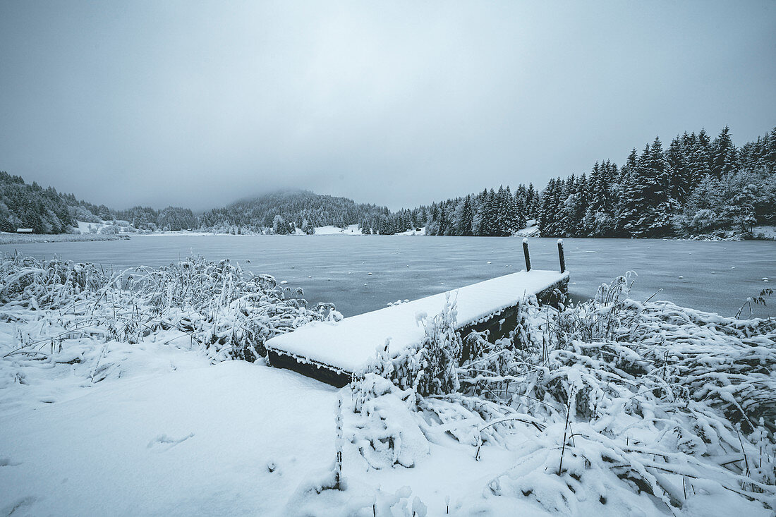 View over the frozen Geroldsee to snow-covered landscape, Krün, Bavaria, Germany.