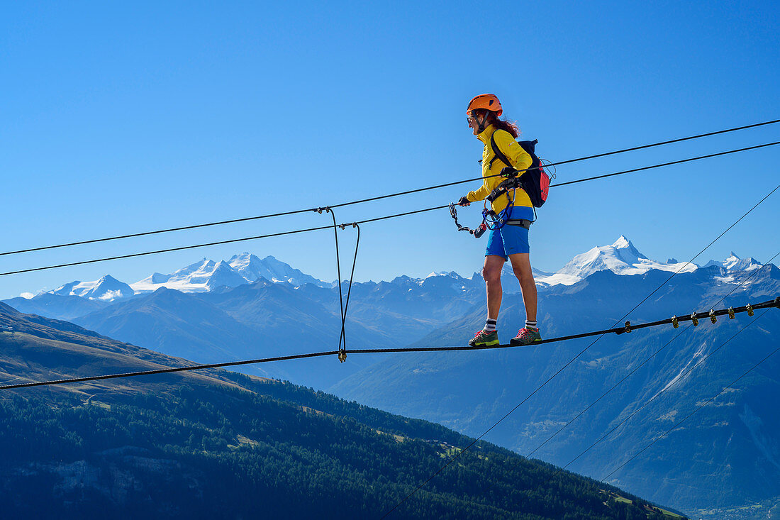 Frau am Erlebnisklettersteig Gemmi geht über Seilbrücke, Walliser Alpen mit Dom und Weisshorn im Hintergrund, Gemmi, Berner Alpen, Wallis, Schweiz