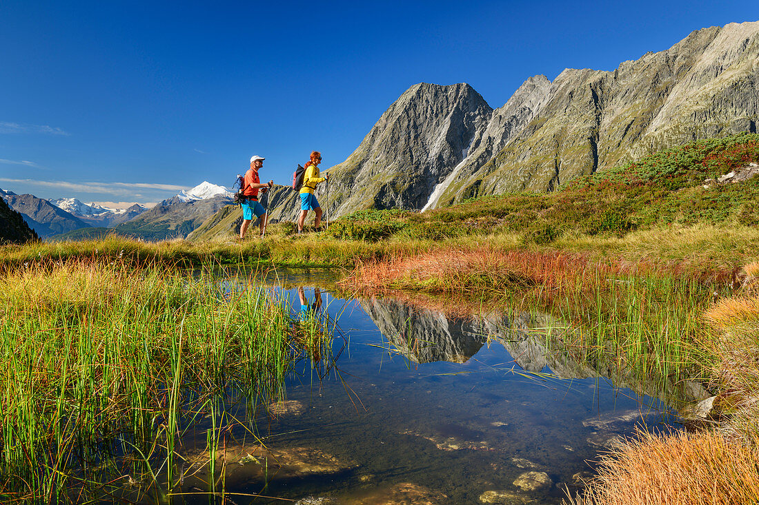 Mann und Frau beim Wandern steigen durchs Baltschiedertal auf, Bergsee im Vordergrund, Wiwannihorn im Hintergrund, Baltschiedertal, Berner Alpen, Wallis, Schweiz