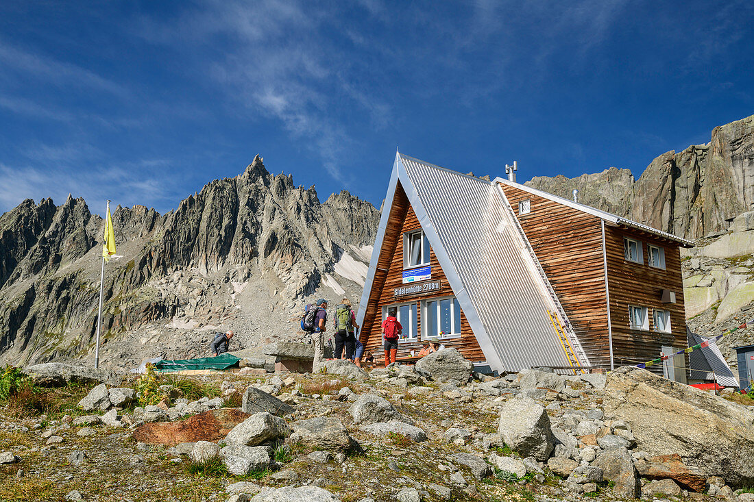 Mehrere Personen stehen vor der Sidelenhütte, Gross Furkahorn im Hintergrund, Sidelenhütte, Urner Alpen, Uri, Schweiz