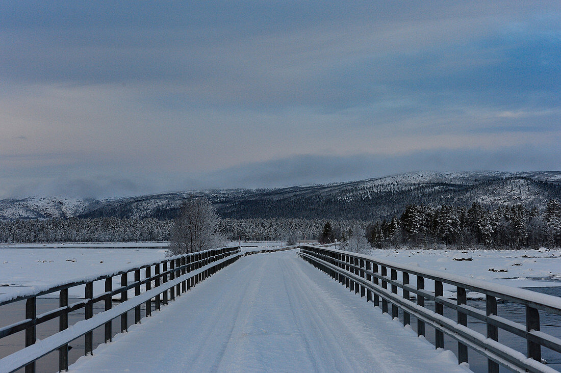 Snow-covered bridge over a lake in winter in Lapland, Arjeplog, Sweden