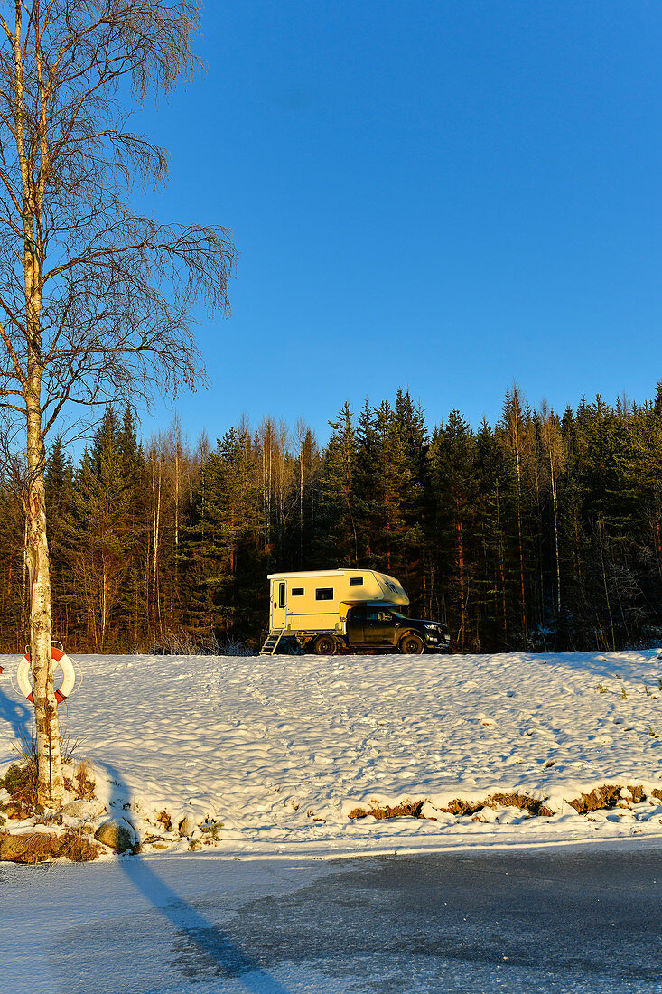 Ein Wohnmobil am verschneiten Ufer eines Sees bei Lycksele, Västerbottens Län, Schweden