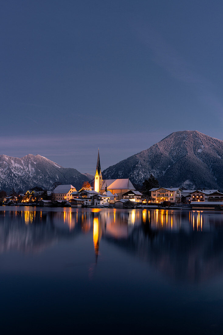 View over the wintry Tegernsee to the village of Rottach-Egern with the church Sankt Laurentius, Bavaria, Germany.