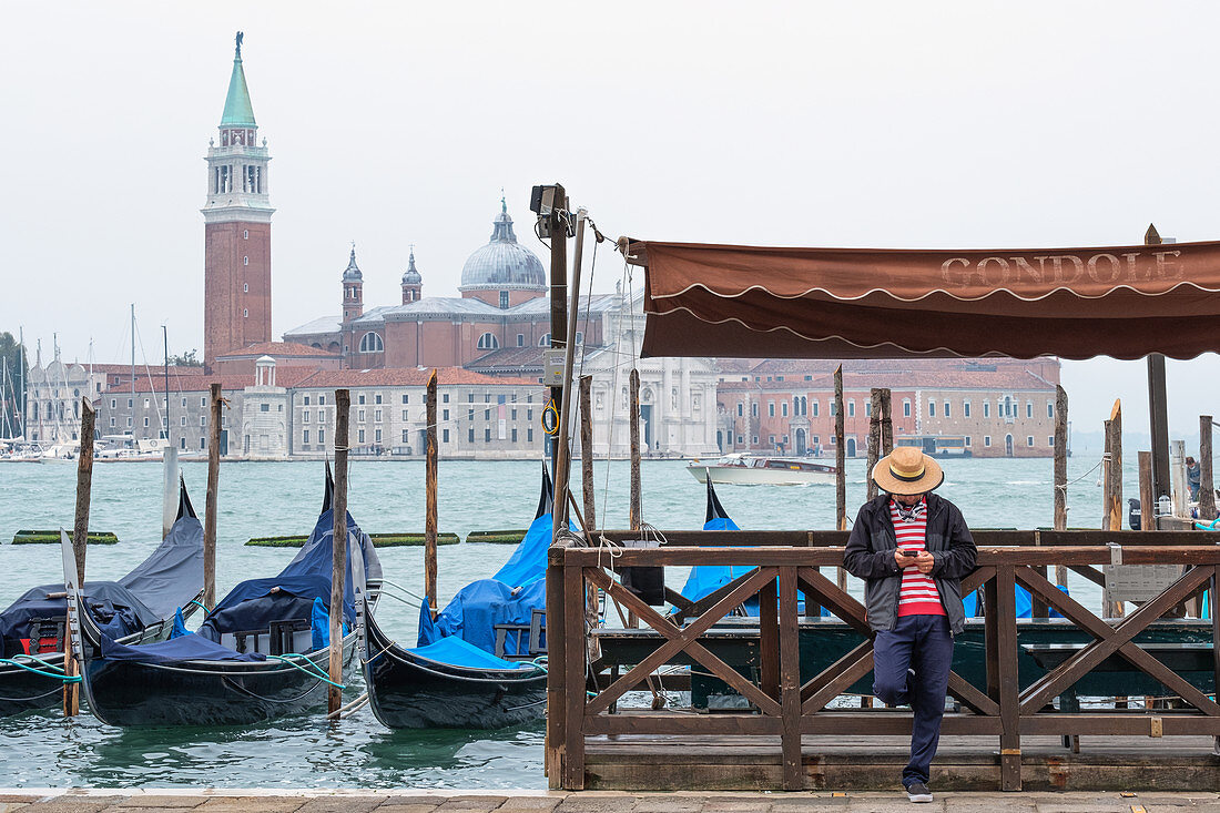 Blick auf die Venezianischen Gondeln und einen Gondoliere am Markusplatz, im Hindergrund die Insel San Giorgio, Venedig, Venetien, Italien, Europa