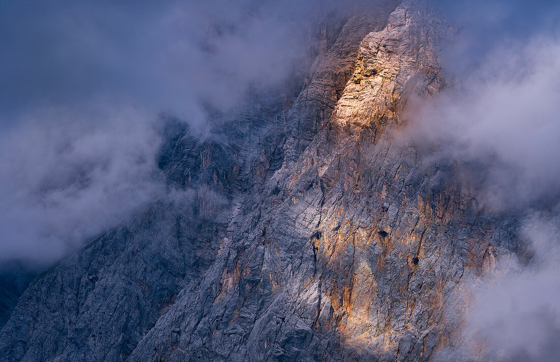 Abendsonne beleuchtet die wolkenverhangene Flanke der Zugspitze, Ehrwald, Tirol, Österreich, Europa