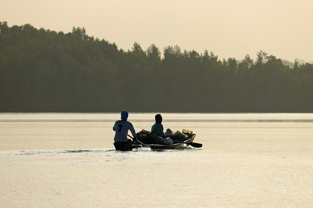 Gambia; Western Region; on the Bintang Bolong; two men sit in a fully loaded boat; drive towards Bintang