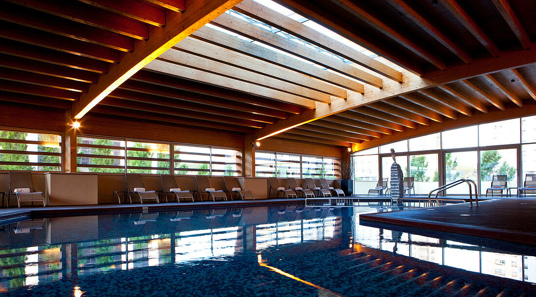 Indoor pool, with rooftop lighting and large windows illuminating the wooden structure, Madrid, Spain.